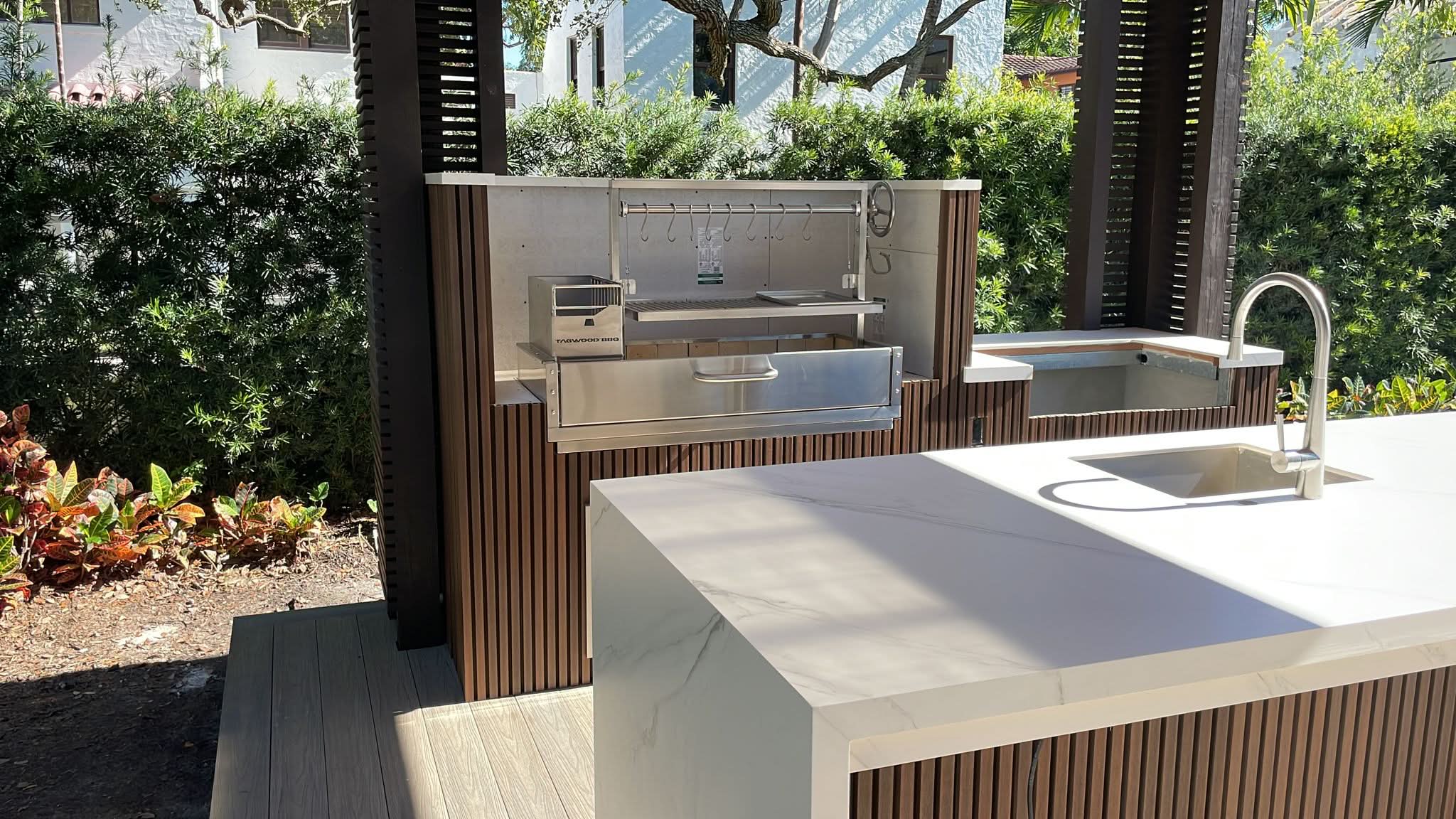 Outdoor kitchen with grill and sink area in a garden setting