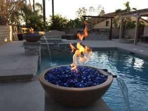 Fire pit with blue glass stones by a pool at sunset