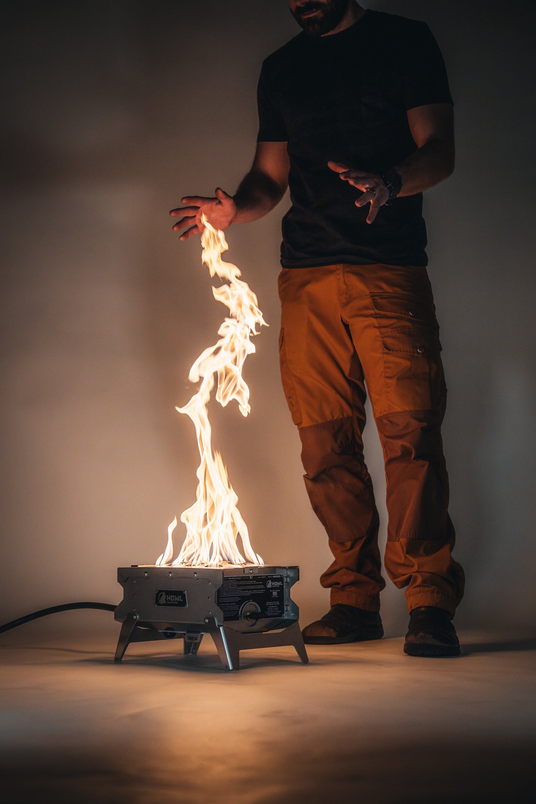 Man warming hands by Howl R1 propane fire pit - Smokeforges