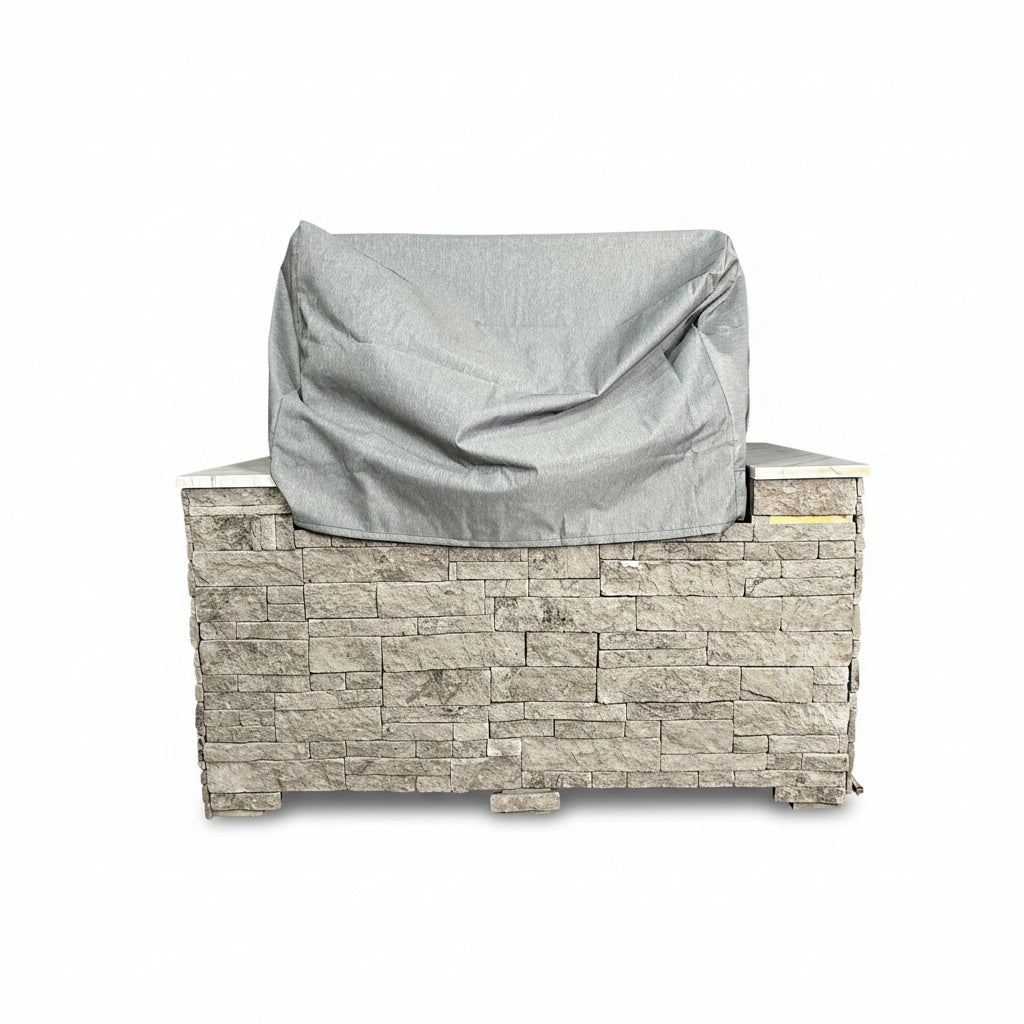A grey fabric cover on a built-in outdoor grill in a stone base -smokeforges