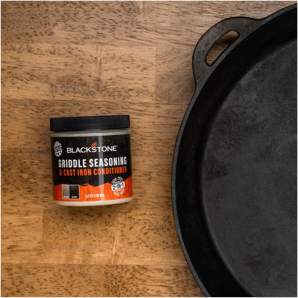 Blackstone Griddle Seasoning and Cast Iron Conditioner — container beside cast iron cookware
